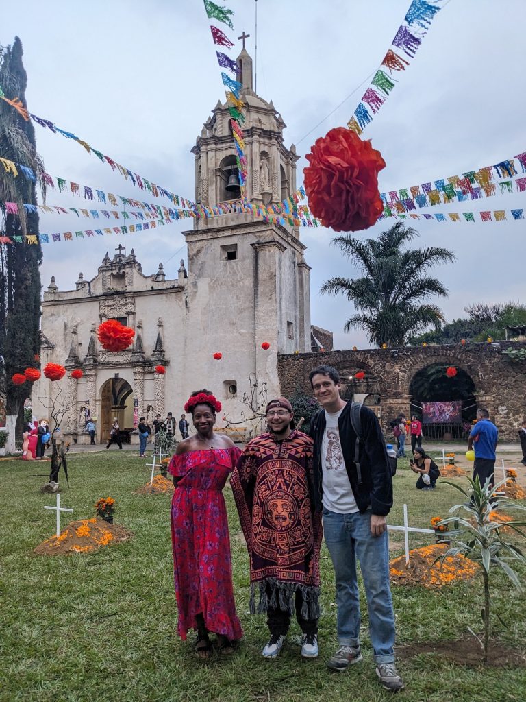 Three tourist posing in front of Day of the Dead decorations at Ocotepec church in Mexico