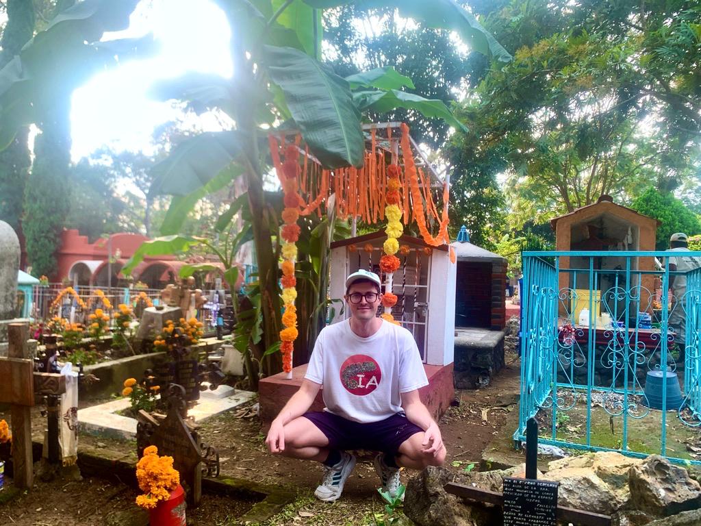 Foreigner poses in front of a decorated grave in Ocotepec cemetery during Day of the Dead