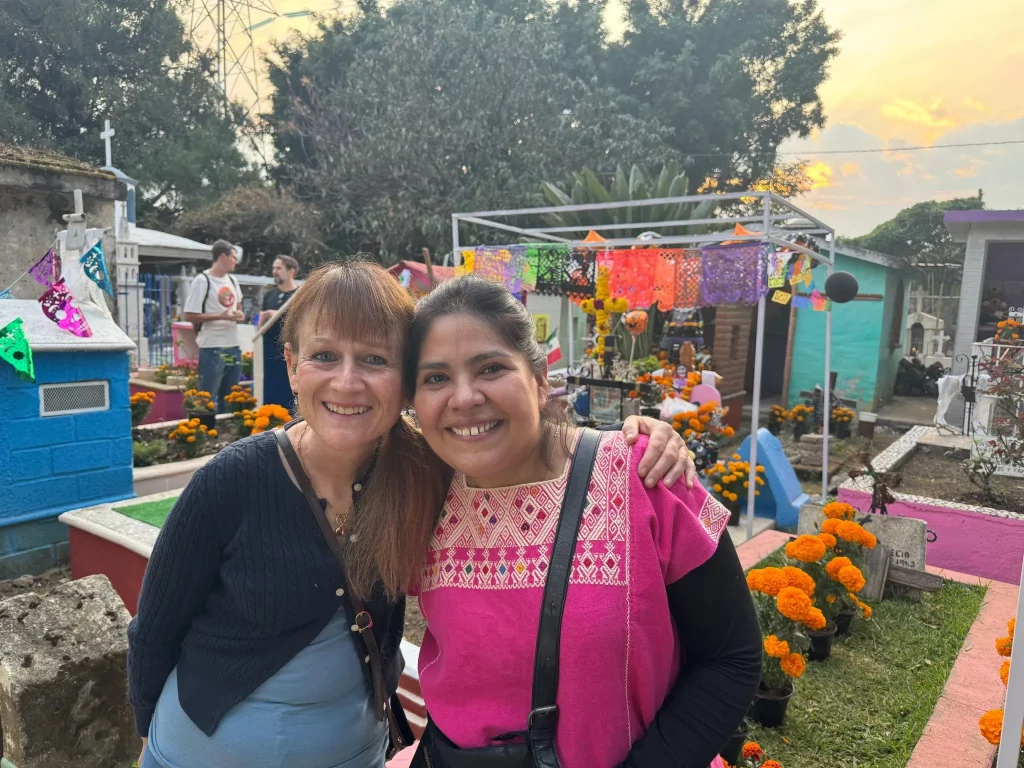 Retiree and Spanish immersion teacher posing in front of day of the dead decorations at the graveyard in Tepoztlan, Mexico