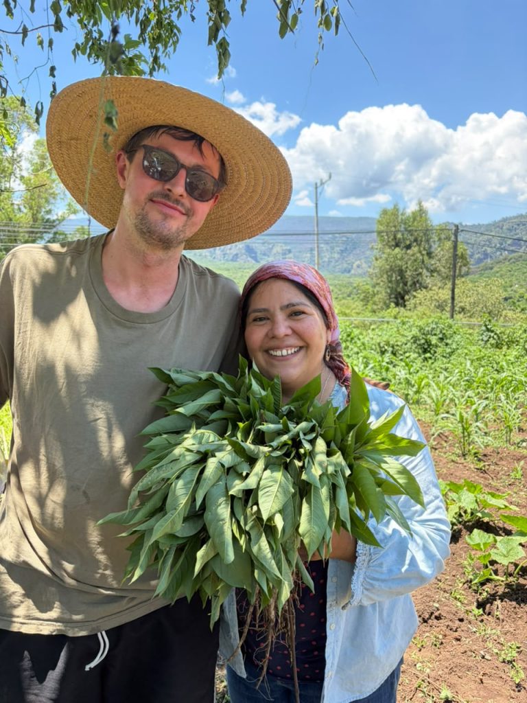 Two people holding a bunch of casahuates in the countryside of Amatlán