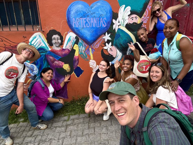 Spanish Immersion students posing next to a wall of colorful street art in Tepoztlan, Mexico
